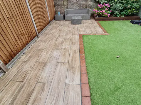 Wood-effect porcelain decking with brick edging and artificial grass