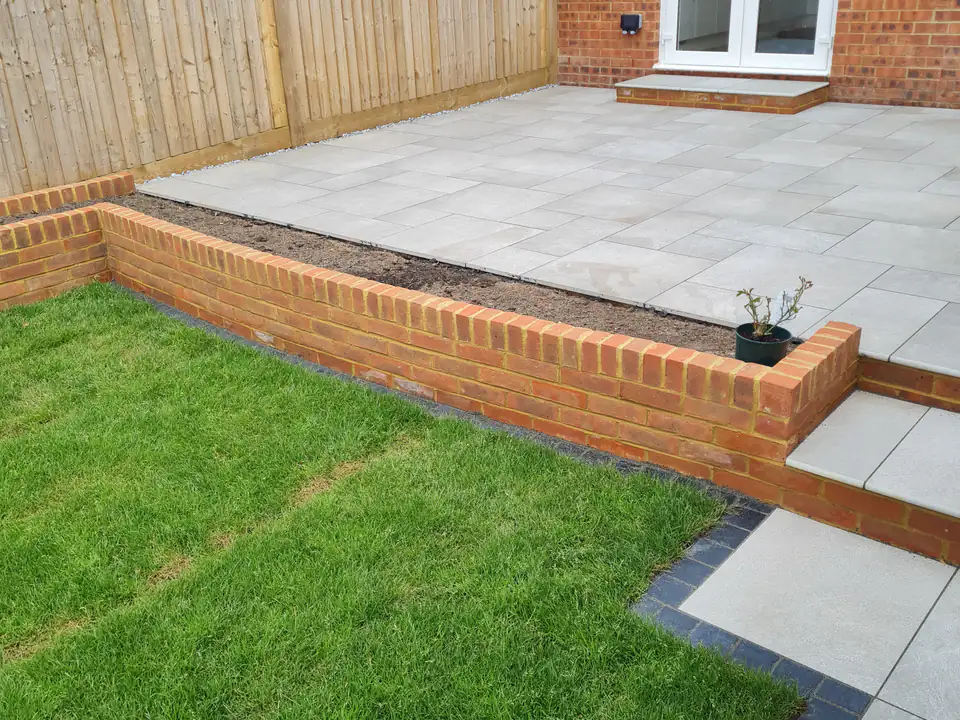 New fencing with a brick-edged raised patio and turf